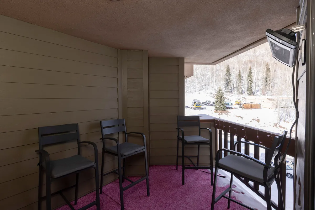 This image captures an inviting outdoor space with black bar stools and a pink rug set against a snowy landscape. The area looks perfect for family members to relax and enjoy drinks while admiring the beautiful winter scenery. The setup suggests easy access to outdoor amenities, echoing the section's emphasis on relaxation and togetherness amid a resort-style environment.