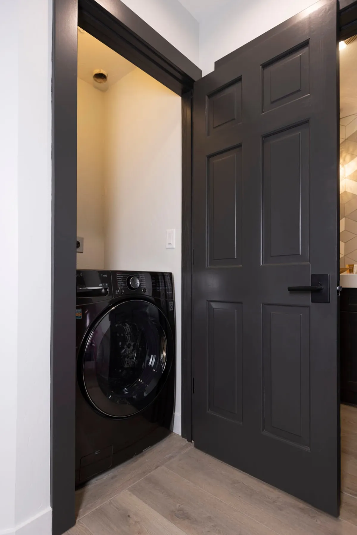 This practical interior image depicts a washing machine and a modern door design, emphasizing the convenience of onsite laundry facilities. The mood is efficient and straightforward, underlining the ease of extended stays.