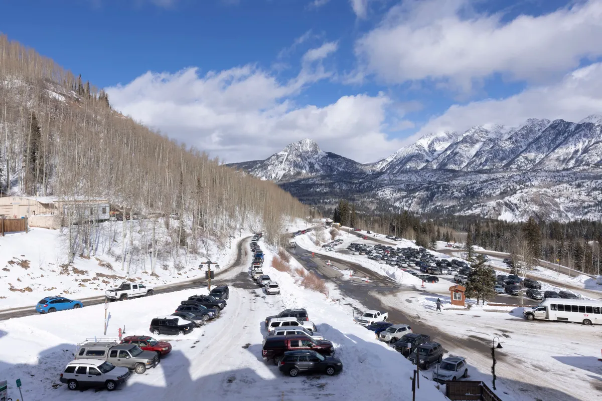 An exterior view featuring snow-covered mountains, aspen trees, and a road with parked cars. This scene encapsulates the resort's mountain setting and proximity to outdoor activities, including skiing and hiking. The image evokes excitement and adventure for the whole family.