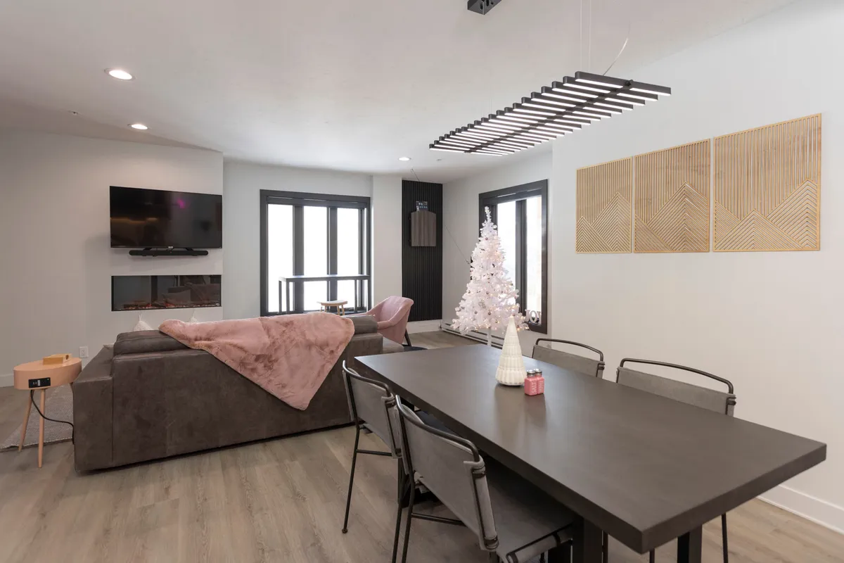 A welcoming dining and living area with a spacious dining table, comfortable sofa, decorative tree, and wall art. The setup is ideal for family dinners, entertaining guests, and relaxing after a day of mountain adventures.